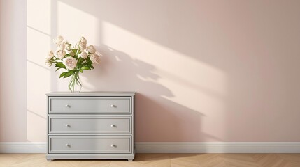 Corner of a room with a light pink wall and a wooden floor. on the left side of the image, there is a white dresser with three drawers.