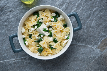 Serving pan with spanakopita pasta on a dark-grey granite background, horizontal shot, top view