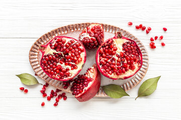 Plate full of fresh ripe pomegranate with cut in half and pieces, top view.