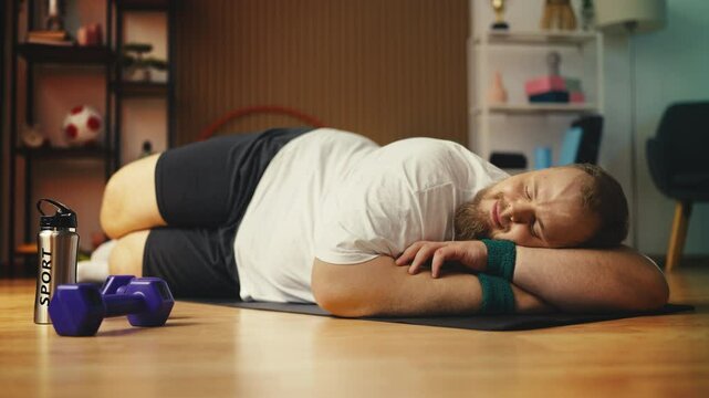 Lazy overweight man sleeping on fitness mat instead of training, procrastination