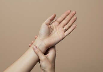 Fototapeta premium Woman Gently Holding Her Wrist Soft Skin Beige Background Elegant Minimalist Photography Studio Shot