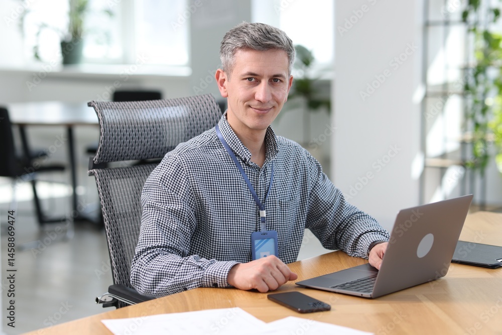 Poster portrait of engineer working with laptop at table in office