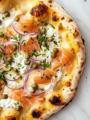 Close-up of a flatbread pizza on a white marble surface. the pizza has a golden-brown crust and is topped with a generous amount of cream cheese, sliced red onions, and smoked salmon.