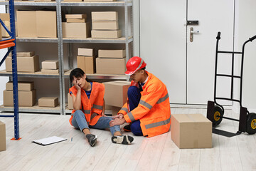 Accident at work. Man helping his injured colleague in warehouse