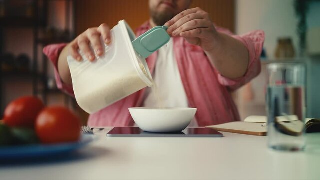 Plus-size man weighing food portions on scale, counting calories for weight loss