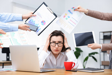 Woman overwhelmed by different requests from colleagues at desk in office