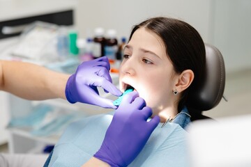 Dentist showing dental mold to young patient in clinic