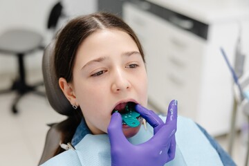 Dentist placing impression tray in girl's mouth for dental care