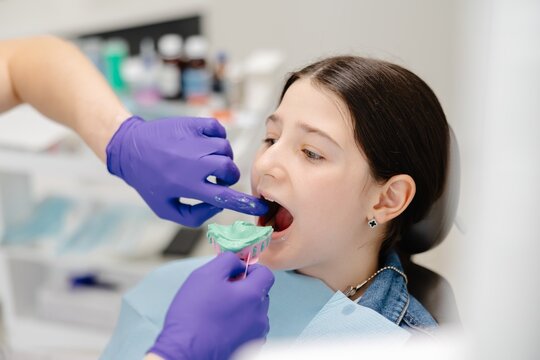 Dentist placing impression tray in girl's mouth for dental care