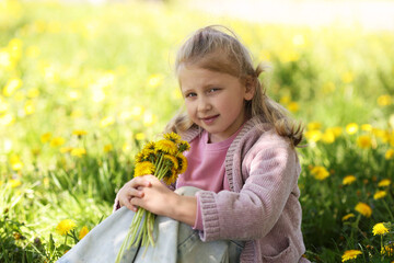 Cute little girl with beautiful dandelions outdoors on sunny day