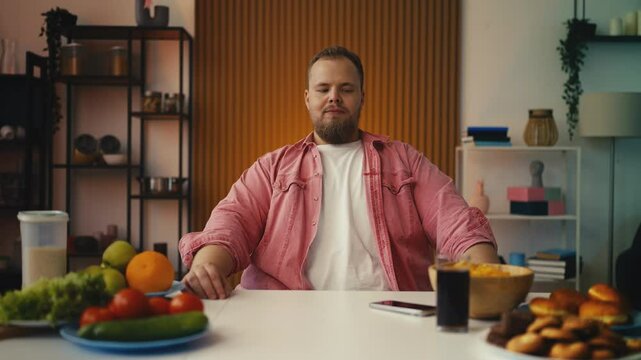 Large-bodied man picking apple over dessert, making healthy diet decision