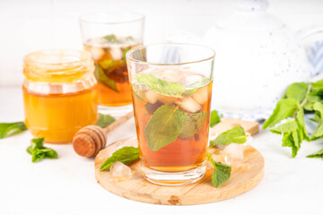 Mint and honey iced tea drink, cold summer refreshment cold beverage with a lot of mint leaves, honey and iced cubes, copy space