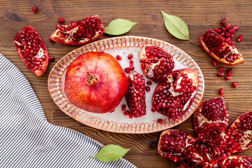 Top view of fresh ripe pomegranate and pieces on plate for eating, top view.