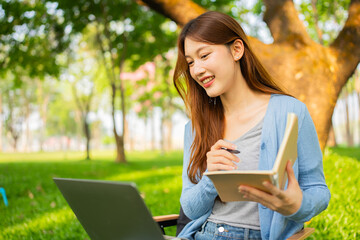 Obraz premium Young Asian woman using laptop to work online in nature