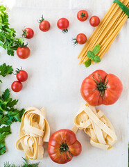 Fresh tomatoes, cherry tomatoes and fresh dry spaghetti for cooking spaghetti. Vertical banner.