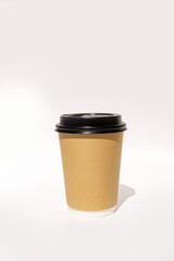 Brown paper coffee cup with black lid on light background