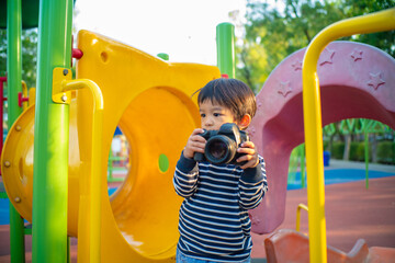 Little kid boy enjoy use camera take photo in city park playground