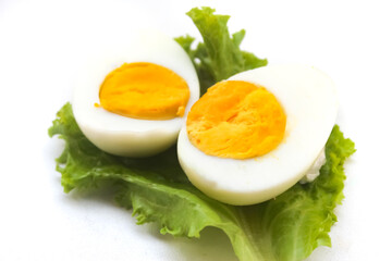 halved boiled egg on lettuce leaf isolated on white background