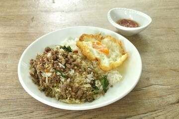 spicy stir fried chop beef meat with basil leaf and chili on rice topping egg in plate dressing fish sauce