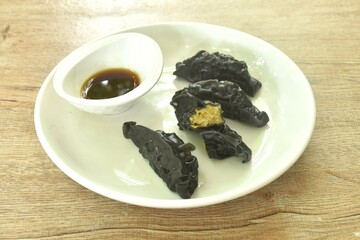 steamed black squid ink Gyoza or Japanese dumpling stuffed mashed pork  curry dipping shoyu sauce on plate 