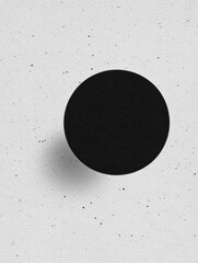 Minimalist black circle on textured white background, creating a striking visual contrast