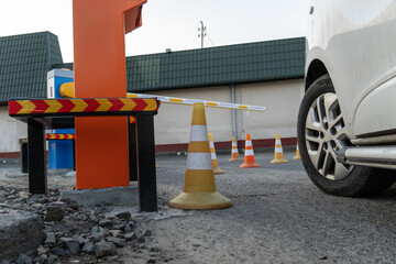 Vehicle at an Orange Barrier Gate with Yellow and White Traffic Cones on Asphalt Parking Lot