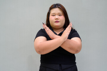 Portrait of a young overweight beautiful Asian woman showing stop gesture for refusal