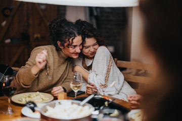 Two friends share a moment of joy and laughter during a warm evening dinner.