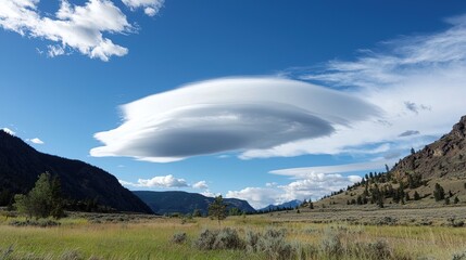 A majestic lenticular cloud hovers over a valley landscape.