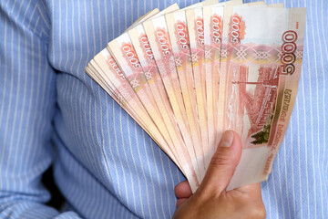 A closeup view of hands presenting an array of vibrant and colorful currency notes, symbolizing finance and economy.