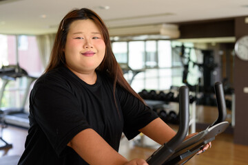 Overweight woman exercising with bicycle in gym