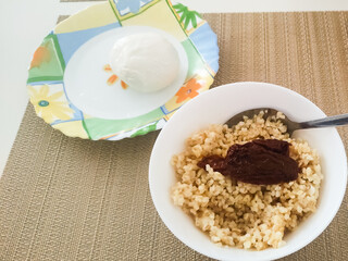 Delicious bowl of cooked grains topped with rich sauce served alongside creamy dessert and refreshing drink