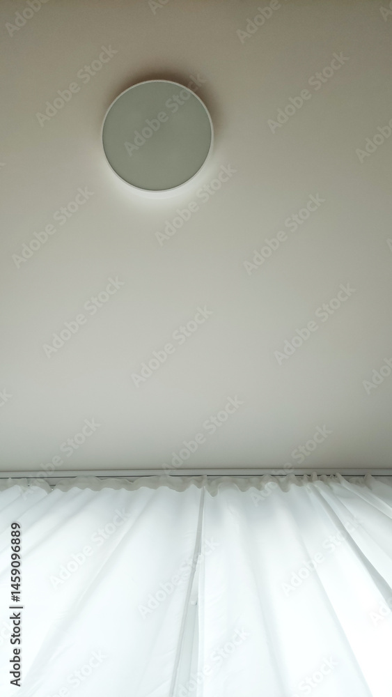 Poster softly illuminated ceiling with circular light fixture and flowing white curtains creating calming a