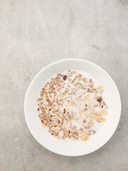 Creamy bowl of oatmeal topped with nuts and fruits on smooth concrete surface showcasing healthy breakfast choice