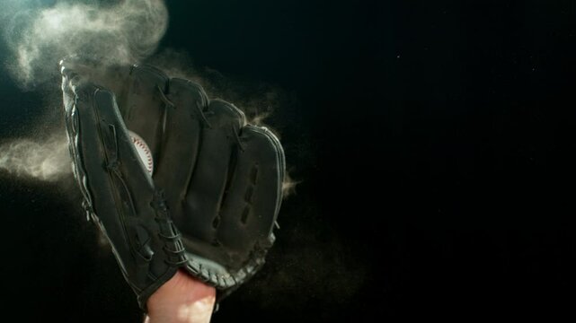 Super slow motion of hand in brown leather baseball glove caught ball isolated on black background . Filmed on high speed cinematic camera