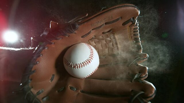 Super slow motion of hand in brown leather baseball glove caught ball isolated on black background . Filmed on high speed cinematic camera