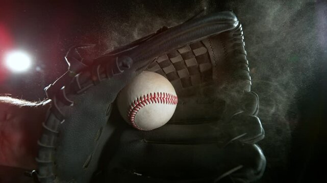 Super slow motion of hand in brown leather baseball glove caught ball isolated on black background . Filmed on high speed cinematic camera