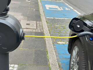 close-up electric car refueling on street charging station, Automotive industry in Europe,...