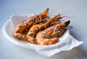 Grilled shrimp served on a white plate on the table.