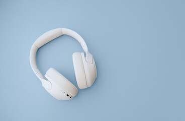 White Bluetooth headphones on a blue background, modern audio technology concept