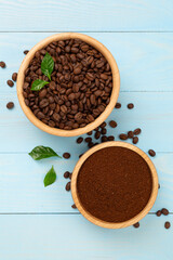 Roasted coffee beans with leaves on wooden background,top view