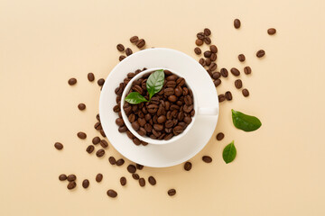 Roasted coffee beans with leaves on color background,top view