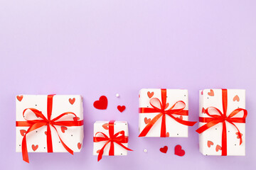 Festive gift boxes with red hearts on color background, top view