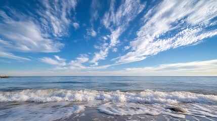 Serene coastal scene featuring gentle waves lapping a sandy shore under a vast, blue sky adorned with wispy, white clouds. : Generative AI