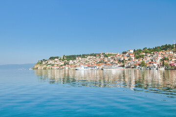 Fototapeta premium Lake Ohrid, North Macedonia, April 13 2024. Mountain range and peninsula in distance. Ohrid Lake, Macedonia, Europe. The clear mesmerizing waters of lake Ohrid with a beautiful view. 