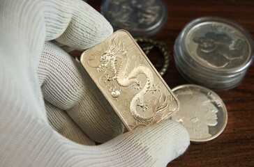 Silver bar with dragon in the appraiser's hand. Finance and Investments.