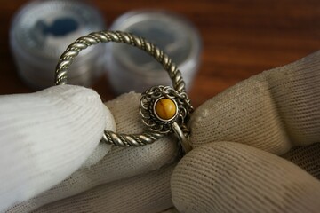 Close-up of an old silver brooch. Old silver jewelry in the hand of an appraiser. 