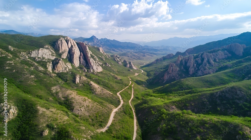 Poster aerial view of a winding mountain road traversing a lush green valley, flanked by imposing rock form