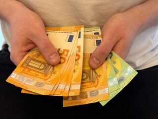Human hands holding and counting money, cash currency euro. A person pays cash, exchanges, received benefits, salary, invests.