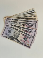Stack of money - US dollars in fifty and ten dollar bills on white background. Pays cash, exchanges, received benefits, salary, invests.
